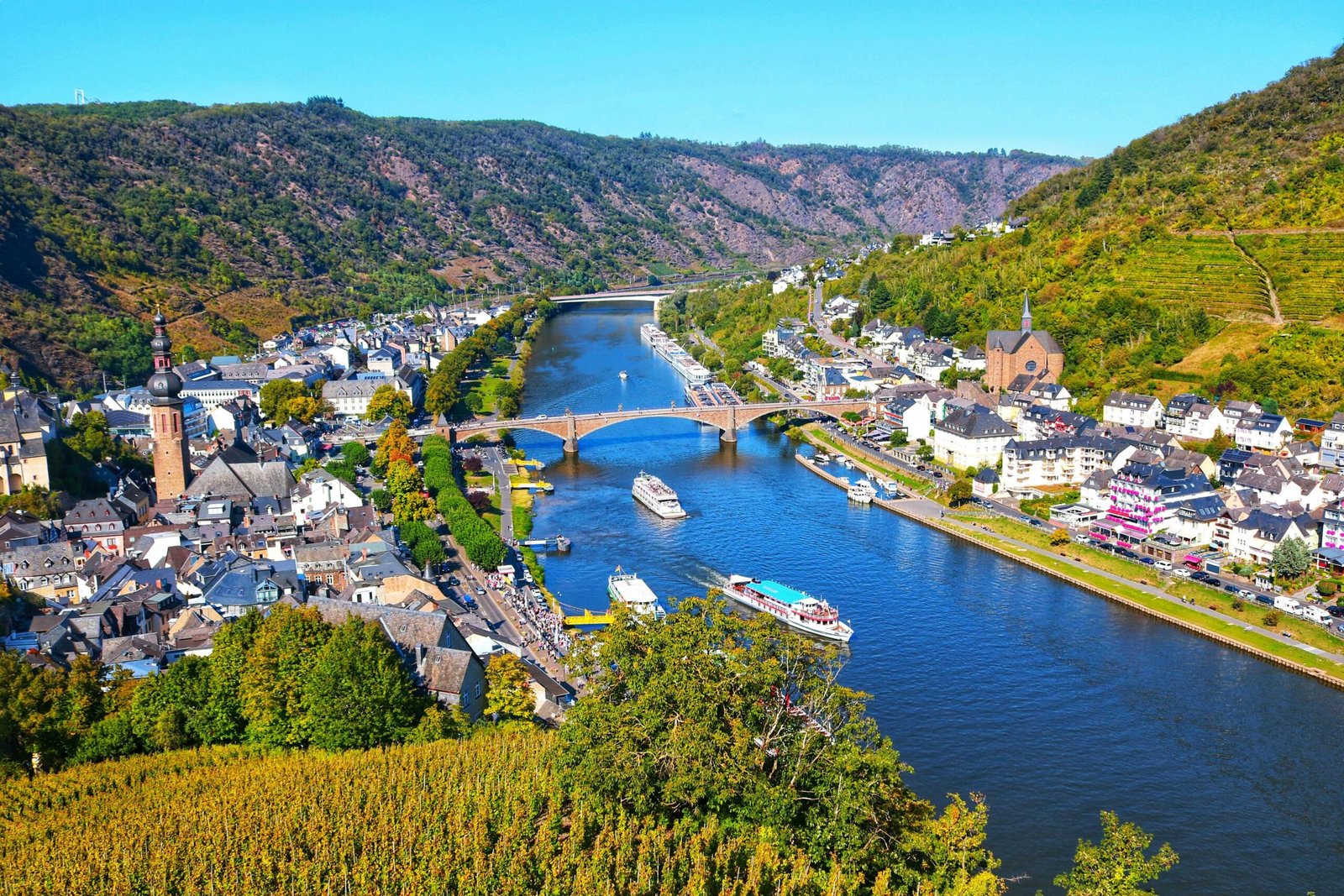 Aerial view of Cochem, Germany with the Moselle River, boats, and lush vineyards.