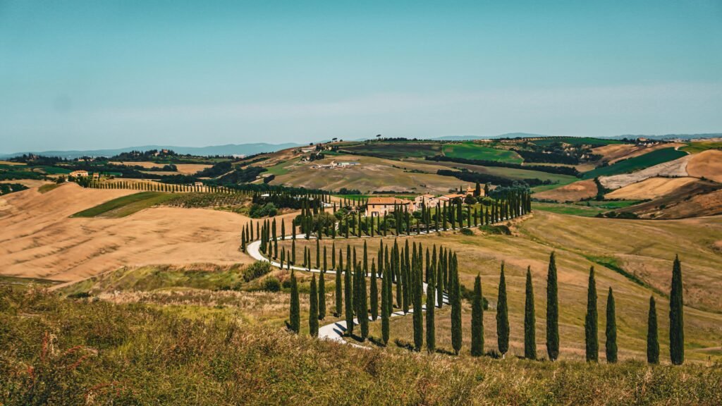 Breathtaking view of rolling hills and cypress trees in Tuscany, Italy, under a clear blue sky.