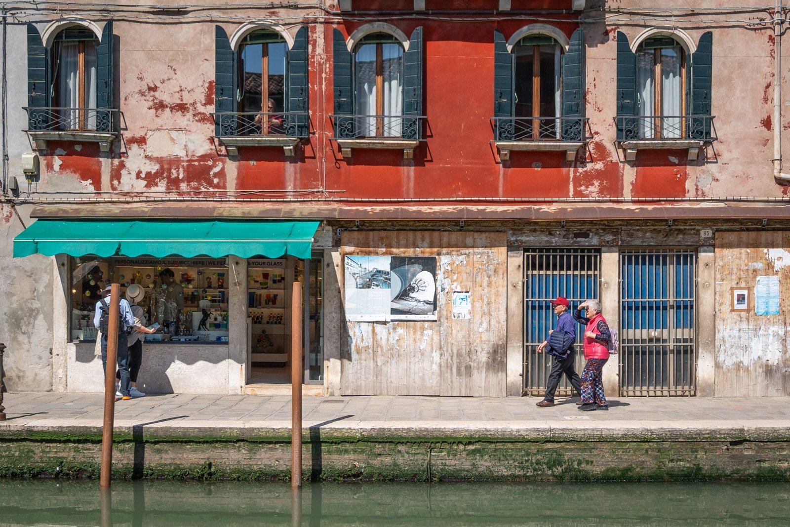 Colorful Venetian street scene with pedestrians along a canal in Venice, Italy.